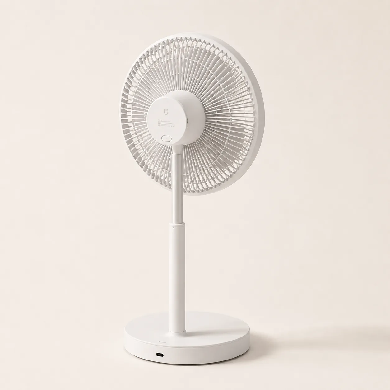 Ventilateur sur pied blanc à hauteur intermédiaire, la tête légèrement inclinée, sur fond crème