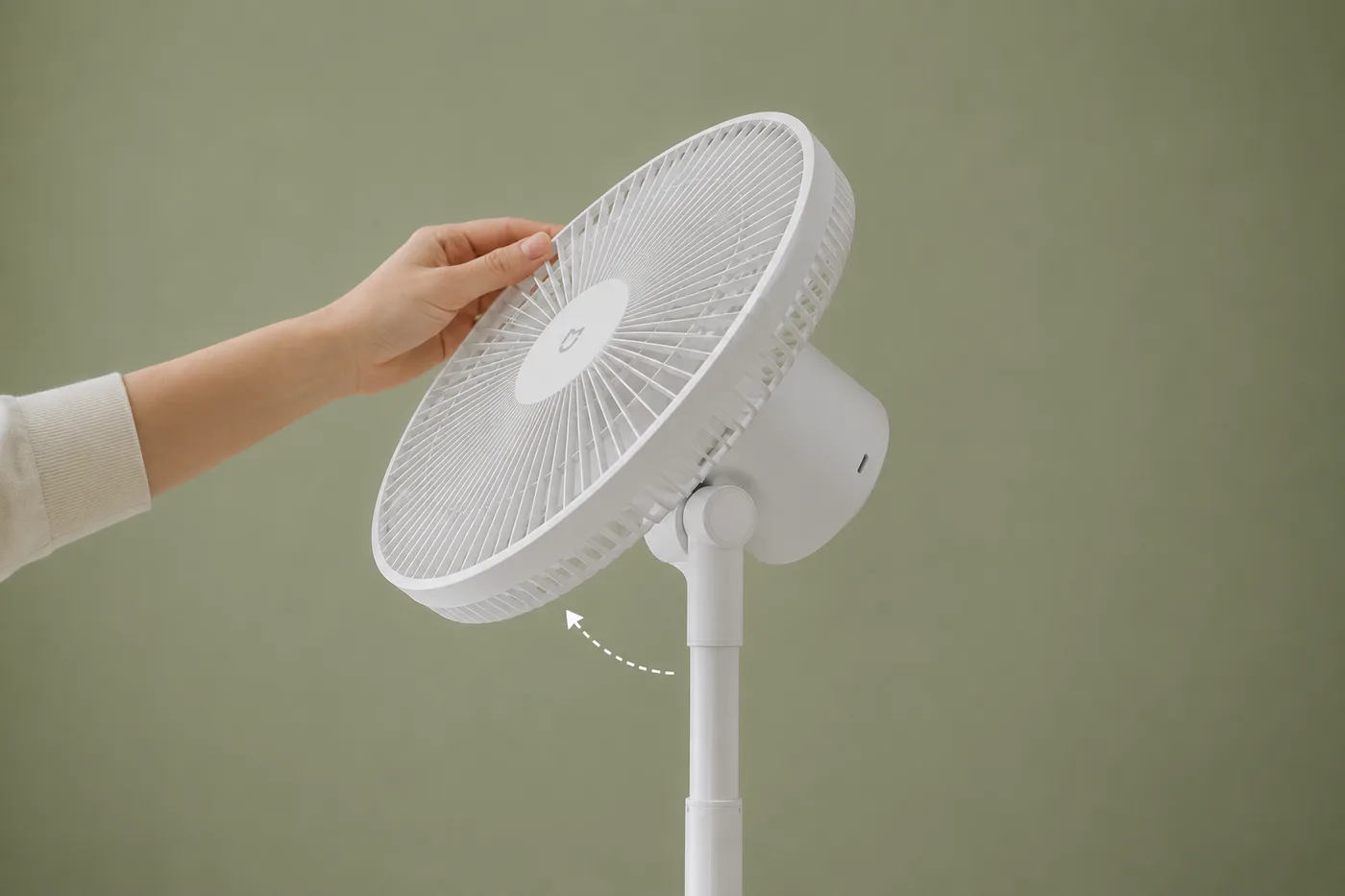 Une main incline la tête du ventilateur vers le bas, sur fond vert