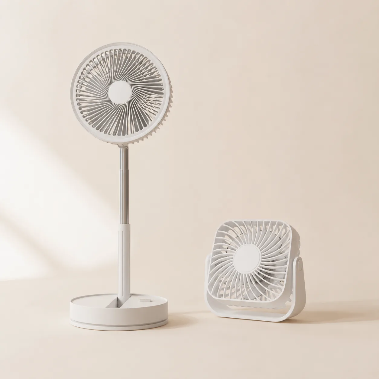 Le ventilateur sur pied blanc posé à côté du petit ventilateur de bureau carré, sur fond crème